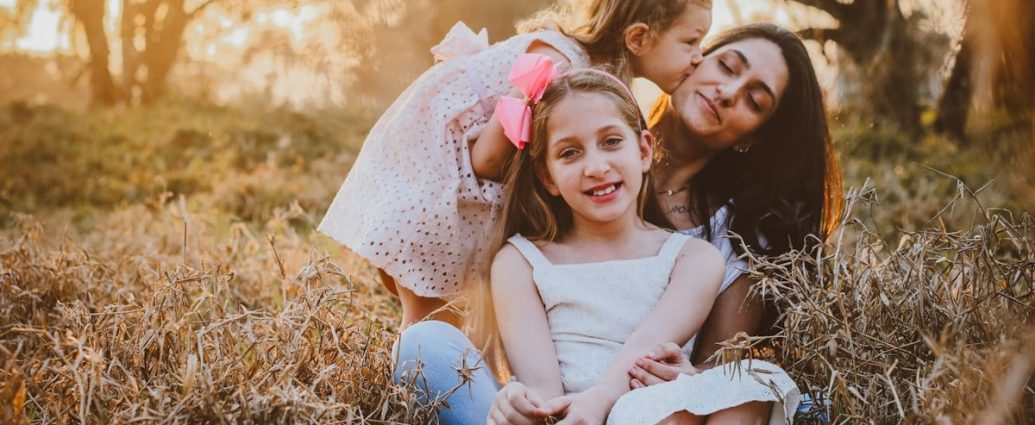 a family of three sitting in a field of tall grass