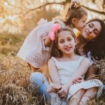 a family of three sitting in a field of tall grass