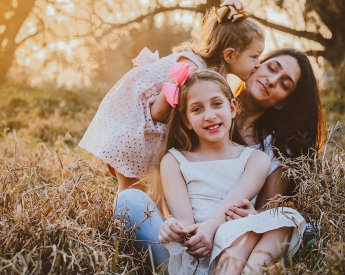 a family of three sitting in a field of tall grass